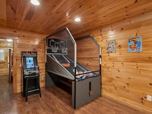 A room with a basketball arcade, wooden walls, and a ceiling with recessed lighting. - Parkside Lodge by Jackson Mountain Rentals (Sevierville)