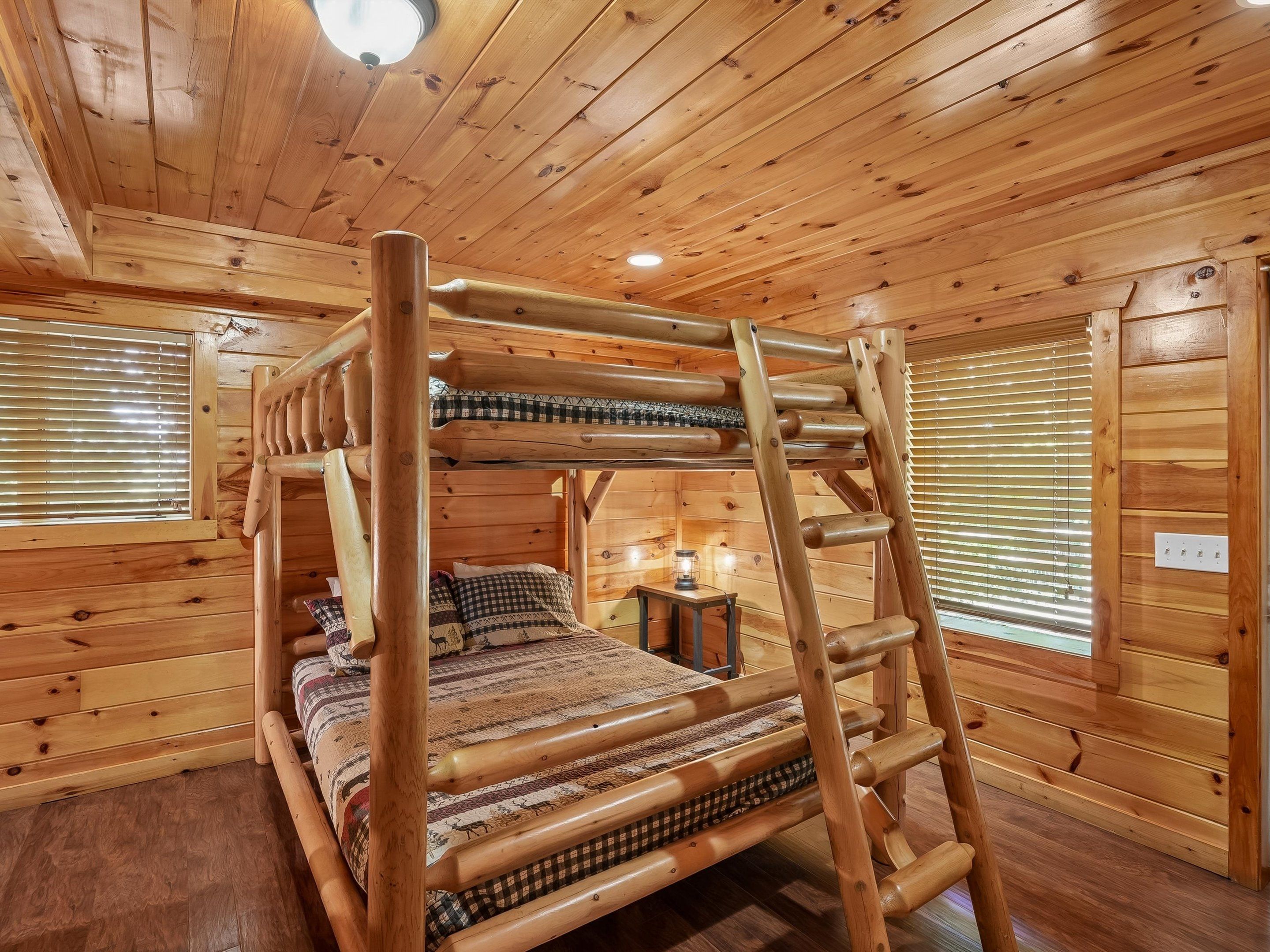 Een stapelbed met een ladder, houten wanden en een raam met zonwering.