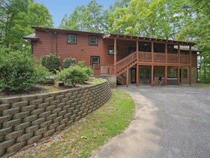 A two-story building with a stone foundation, a wooden deck, and a brick retaining wall.