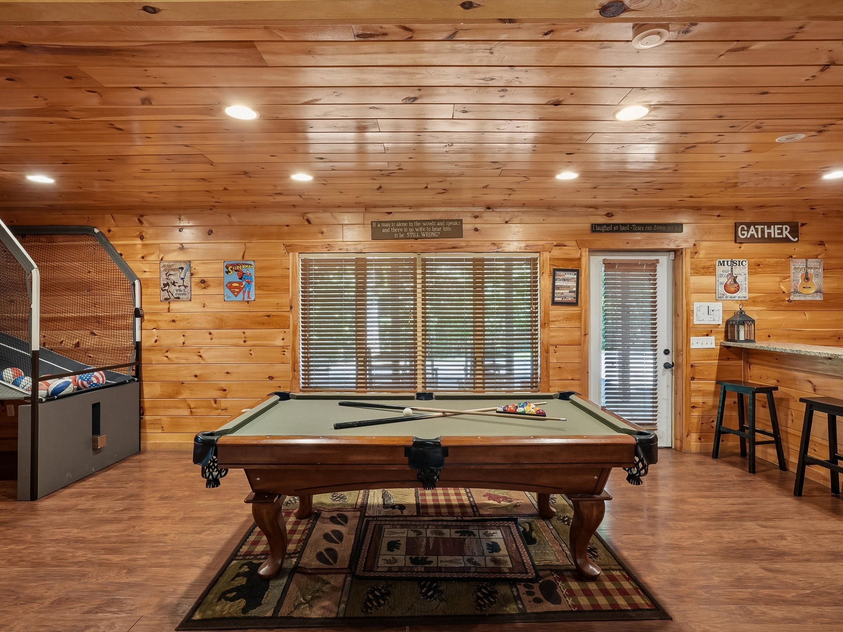 A pool table in a room with wooden walls and a ceiling with recessed lighting.