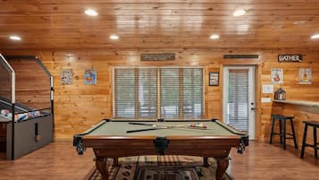 A pool table in a room with wooden walls and a ceiling with recessed lighting.