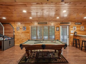 A pool table in a room with wooden walls and a ceiling with recessed lighting.