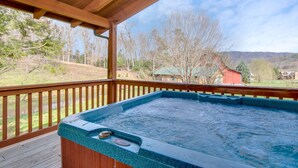 Un jacuzzi en una terraza de madera con vistas a un paisaje rural.