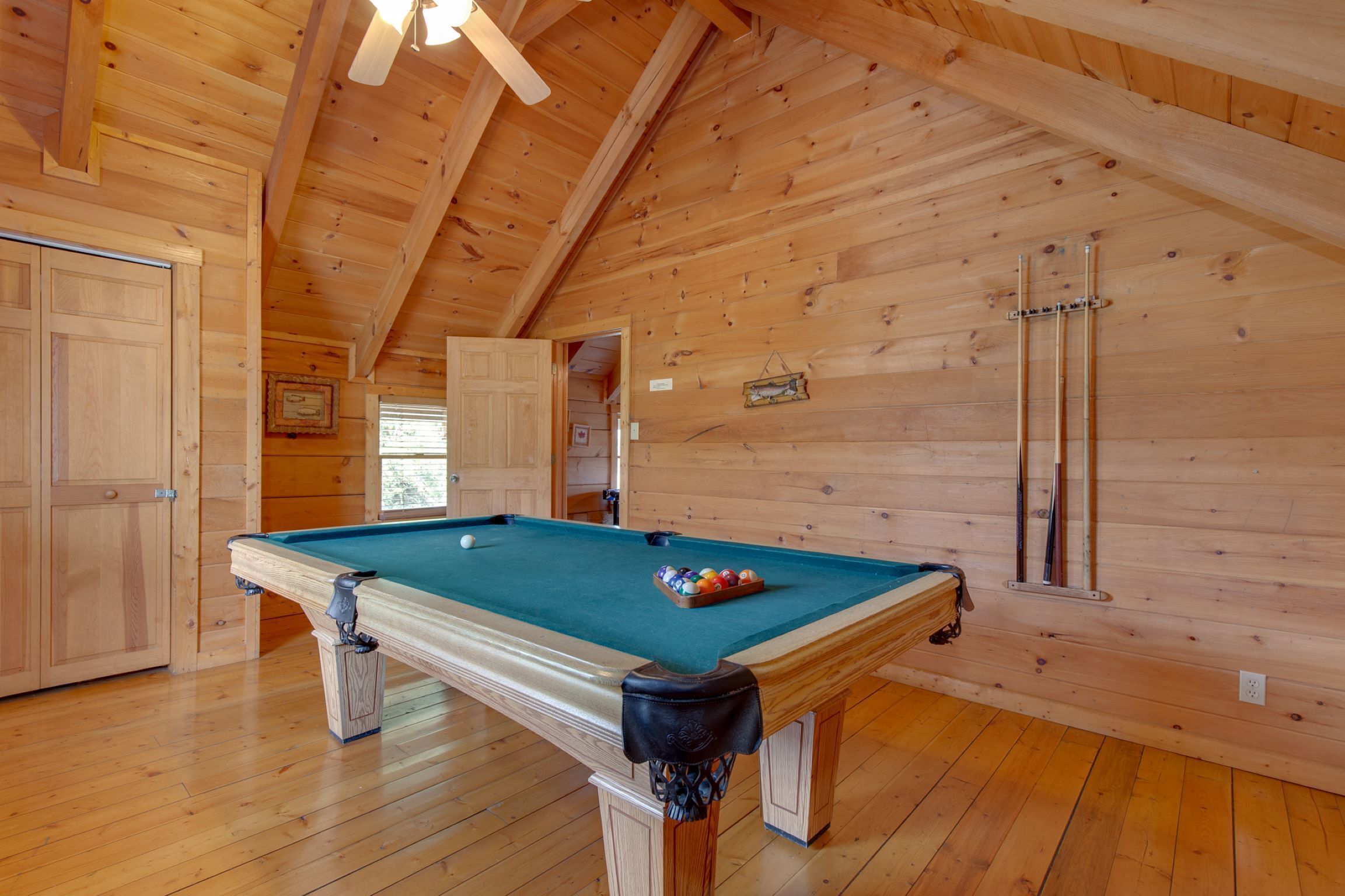 Une pièce en bois avec une table de billard, des murs en bois et une porte.