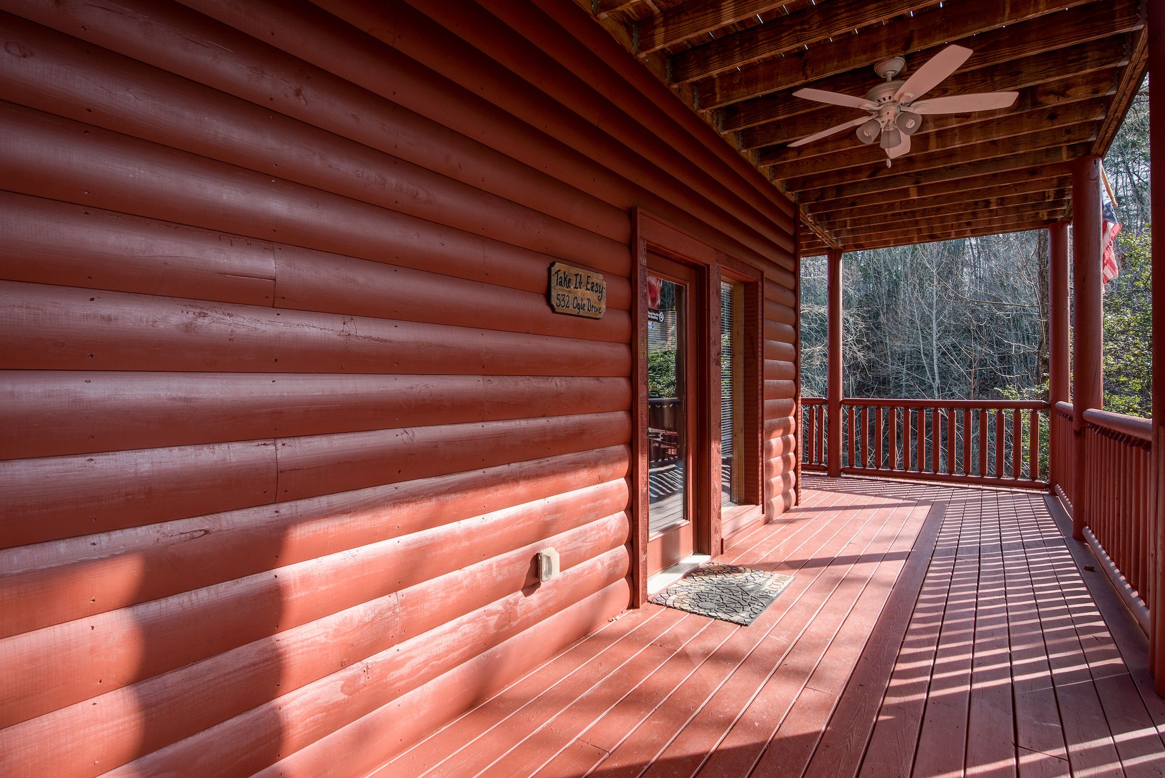 A wooden cabin with a covered porch and a sign reading "Take It Easy 5320 Olde Drive".