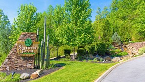 A sign for Sherwood Forest with a stone wall and wooden fence, surrounded by lush greenery and trees. - Aspen's Envy by Jackson Mountain Rentals (Pigeon Forge)