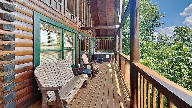 A wooden deck with a bench and chairs, a hot tub, and a view of greenery. - Aspen's Envy by Jackson Mountain Rentals (Pigeon Forge)