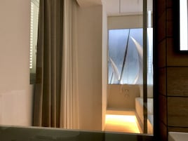 Un bagno moderno con cabina doccia in vetro, un water a vista e uno specchio che riflette l'ambiente.