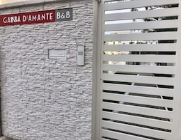 Un muro in pietra con un cartello che riporta “GABBA D'AMANTE B&B” e un tastierino per l'ingresso.