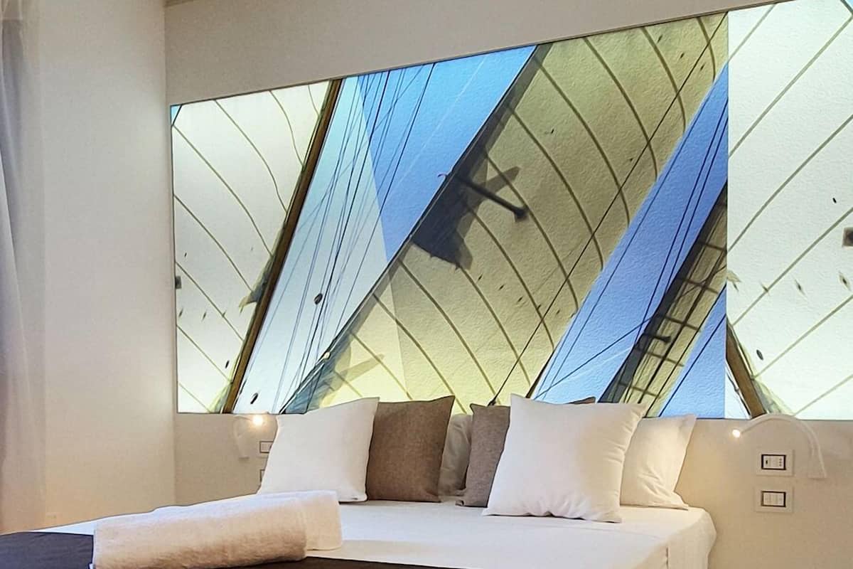 Quarto moderno com uma cama grande, um claraboia e piso de madeira.