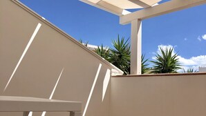 A covered outdoor area with a white ceiling structure, a white wall, and a tiled floor. - B&B Gassa D’Amante (Vieste)
