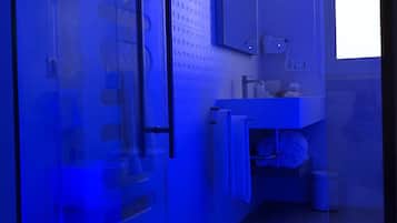Un baño moderno con cabina de ducha de vidrio, lavabo con espejo y ventana que proporciona luz natural.