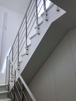 Una moderna scala con ringhiere in metallo e una parete bianca.