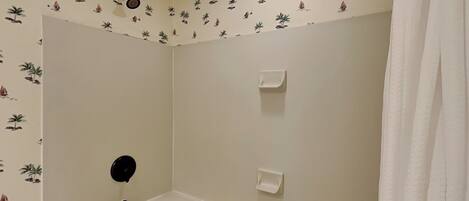 Un baño con bañera, cortina de ducha y un muro con estampado tropical.