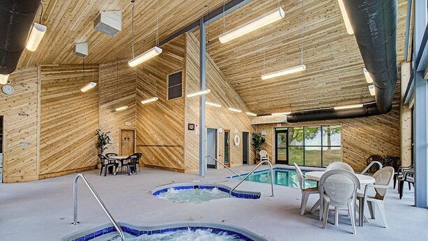 A spa area with two hot tubs, wooden walls, and a pool table. - Summit of Gatlinburg by Jackson Mountain Rentals (Gatlinburg)