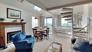 A spacious living room with a fireplace, a dining area, and a spiral staircase leading to a bedroom. - Summit of Gatlinburg by Jackson Mountain Rentals (Gatlinburg)