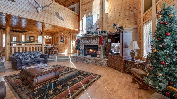 Ein großzügiges Blockhaus-Interieur mit Kamin, Weihnachtsbaum und einer gemütlichen Sitzecke.