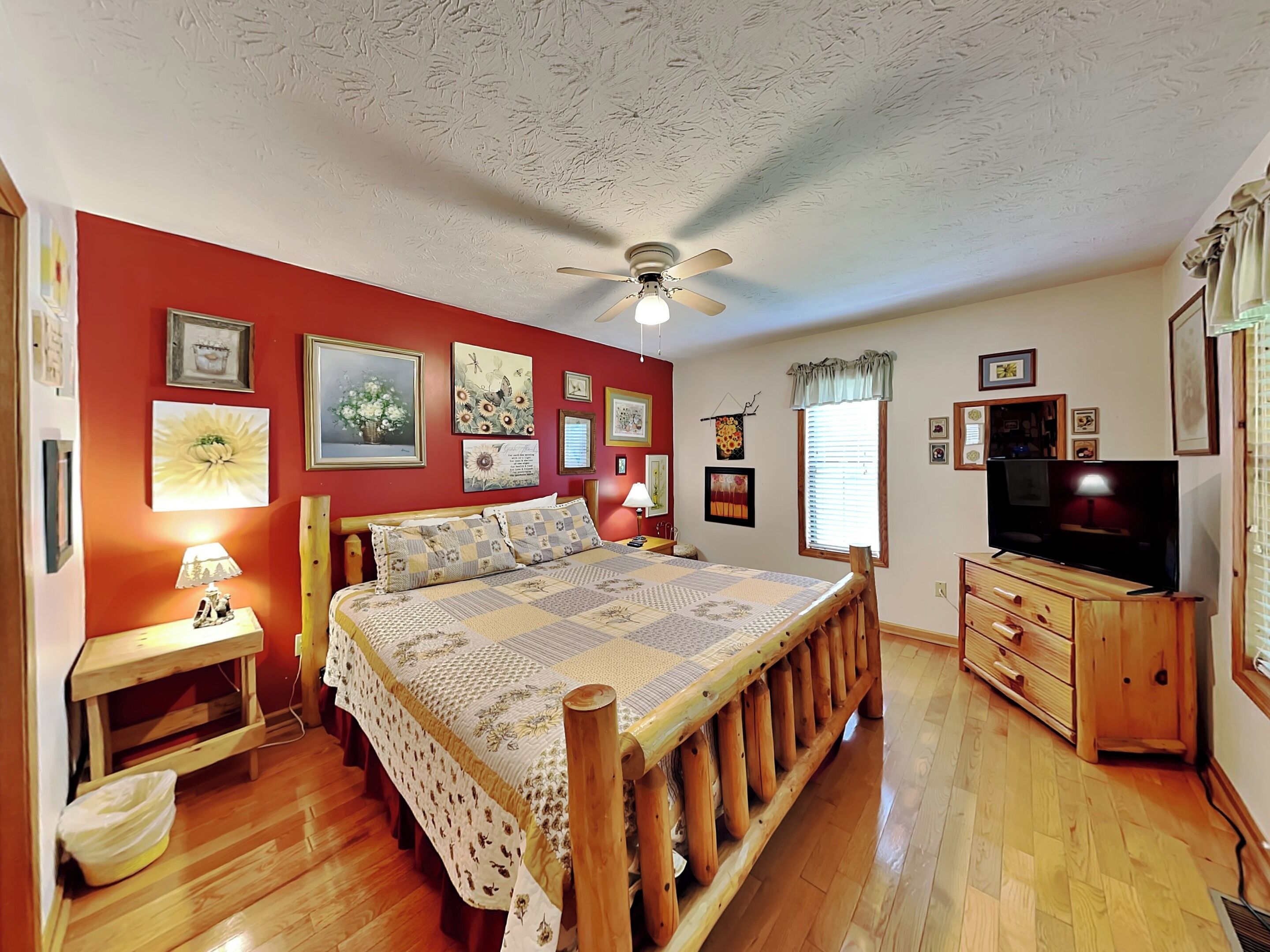 A bedroom with a wooden bed, a ceiling fan, and a TV.