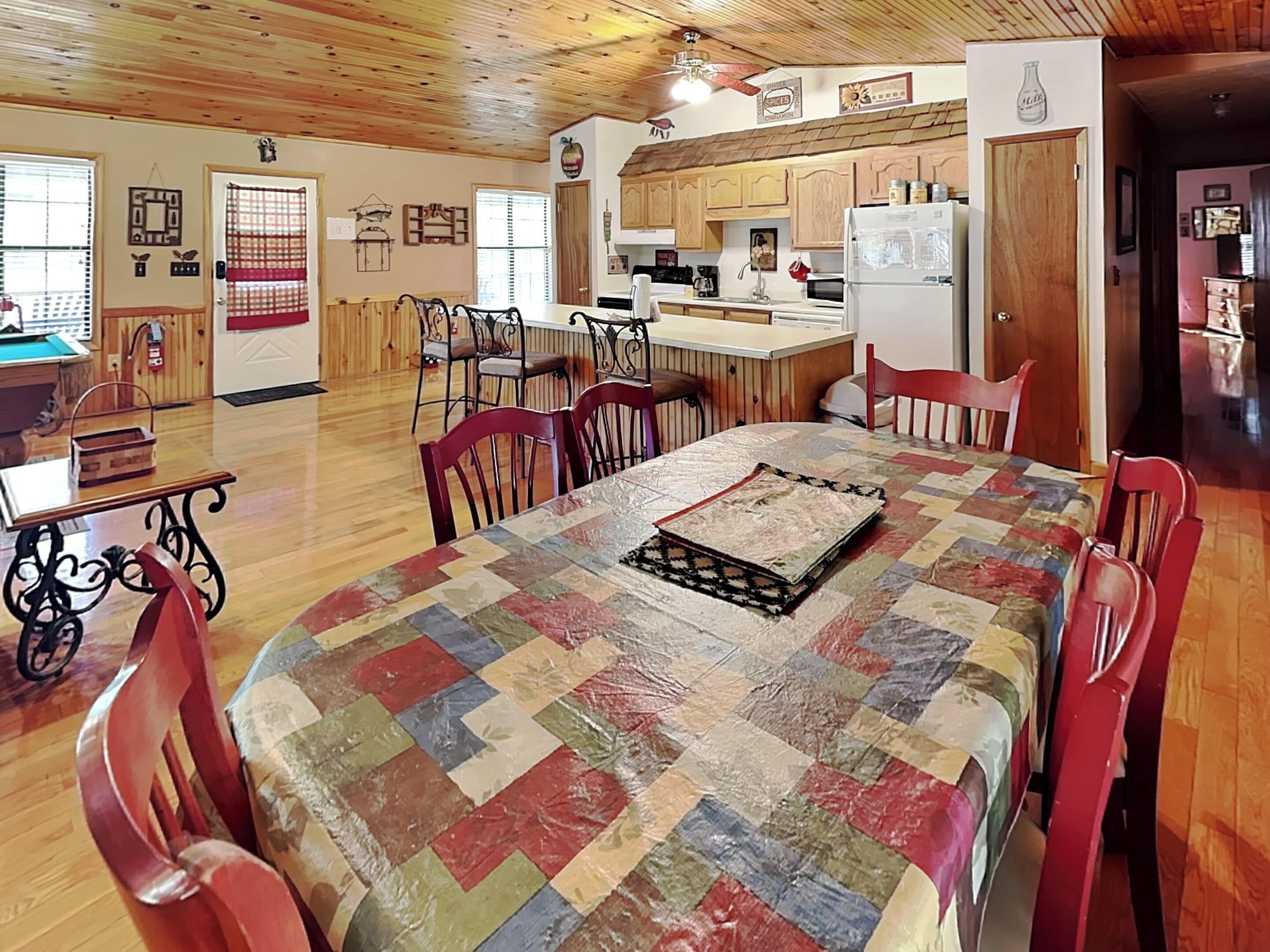 Una cocina amplia con armarios de madera, una mesa de comedor con sillas y un refrigerador.