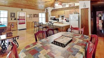 Una cocina amplia con armarios de madera, una mesa de comedor con sillas y un refrigerador.