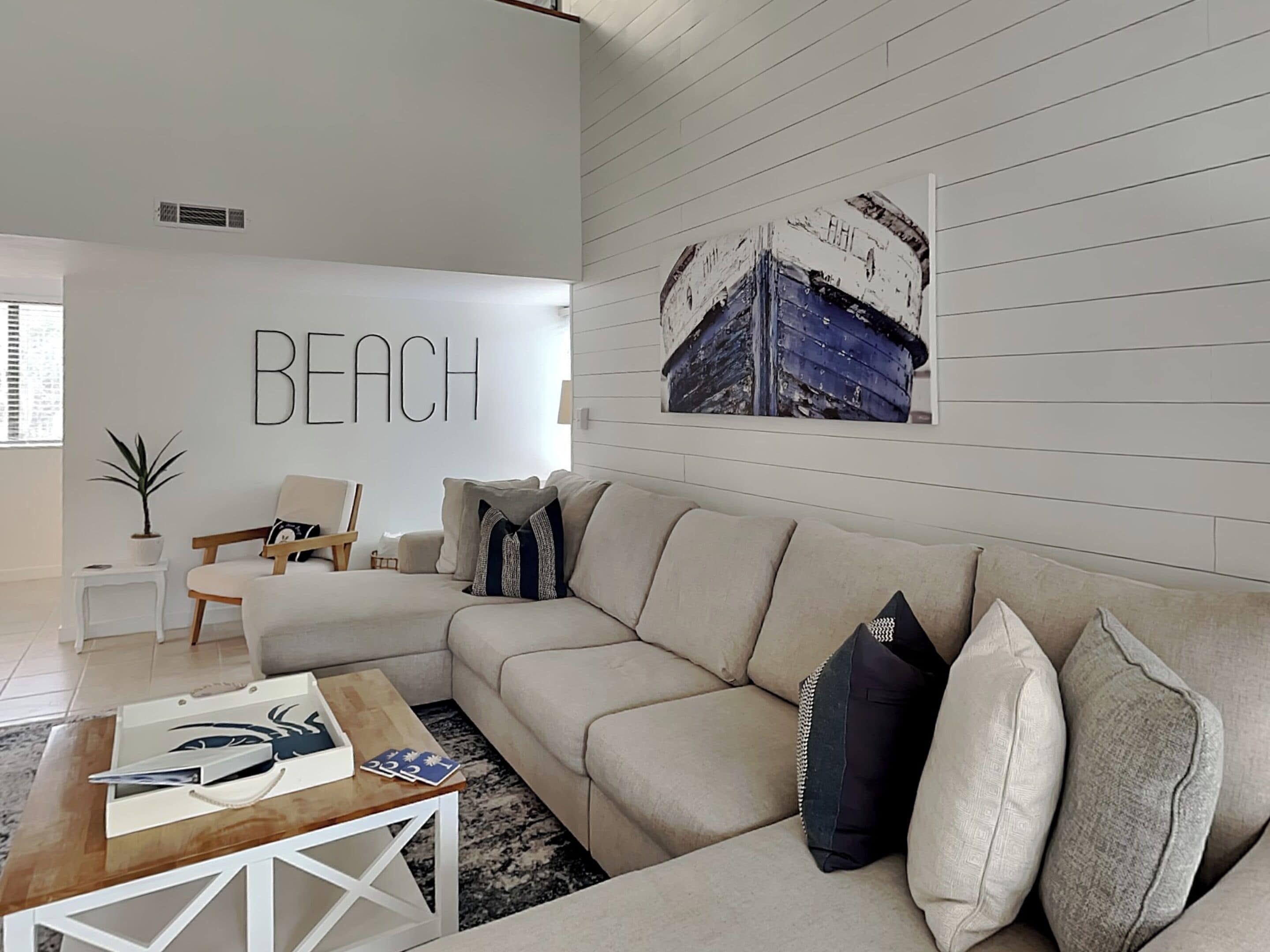 A modern living room with a beige sofa, a wooden coffee table, and a wall-mounted artwork depicting a boat.