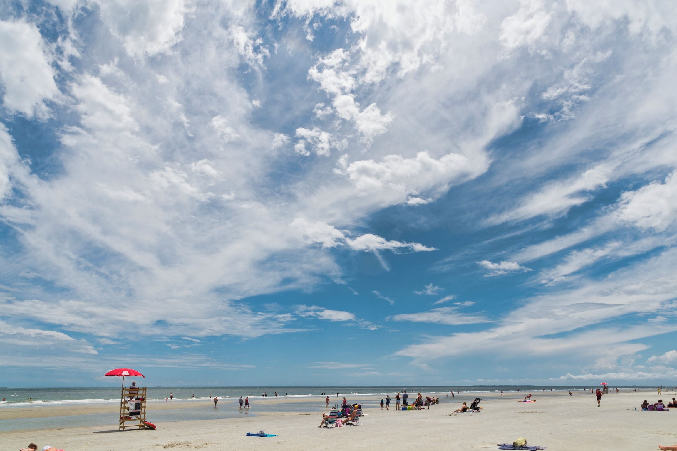 A beach scene with a lifeguard tower and beachgoers.