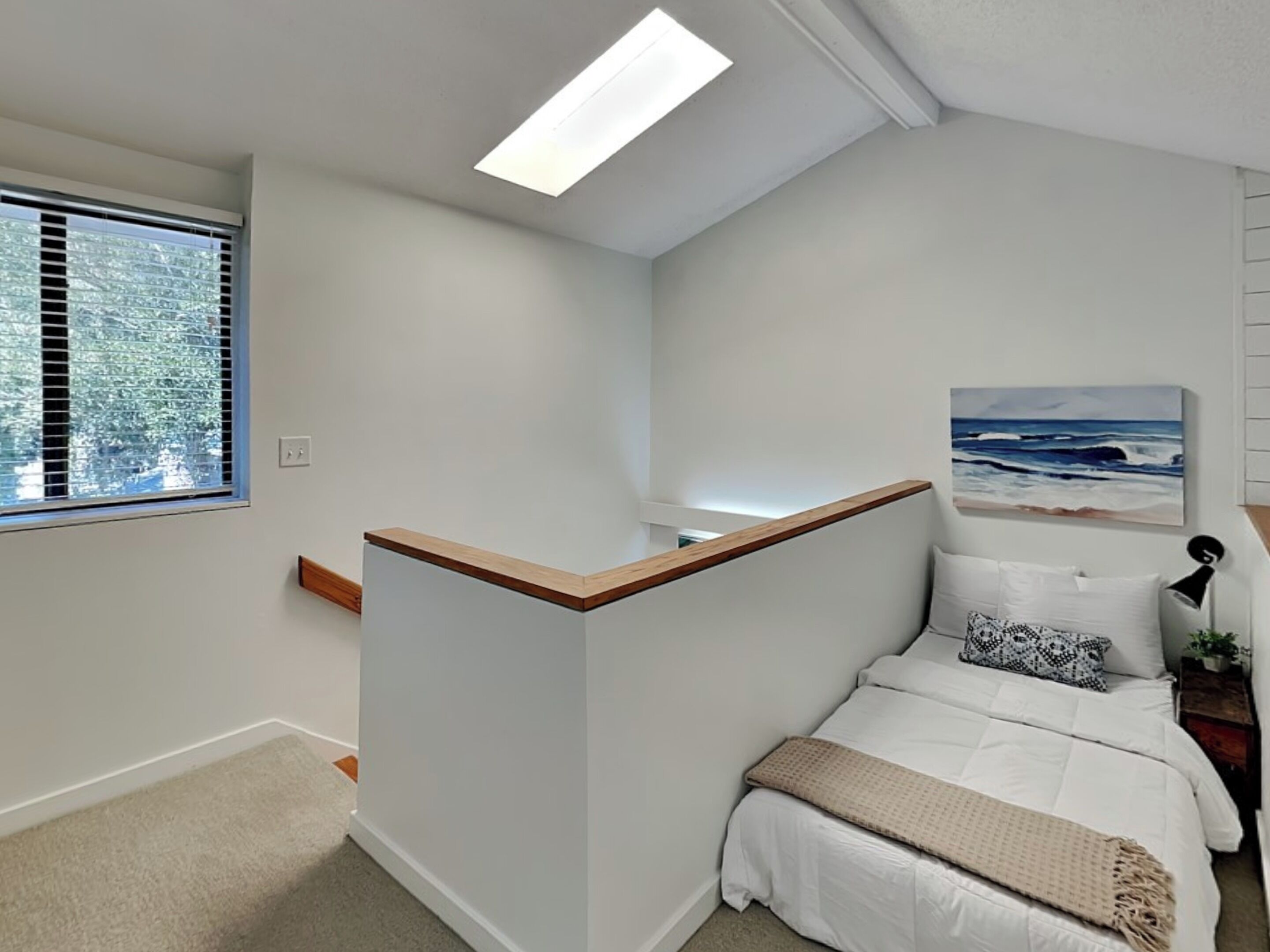 Un dormitorio con cama, un cuadro, una lámpara y una ventana con persianas.