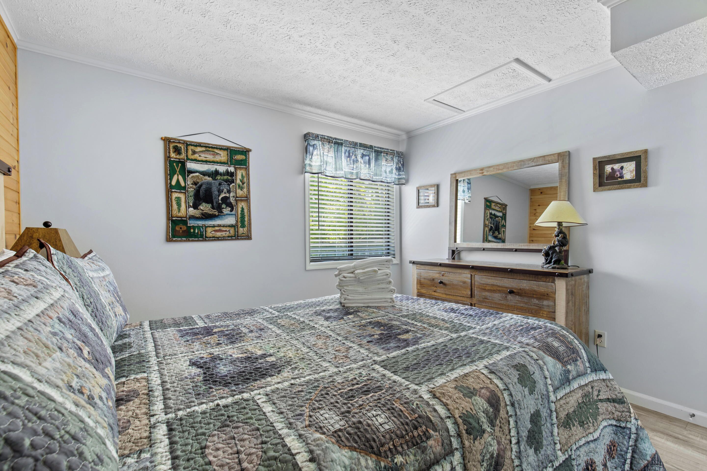 A bedroom with a large bed, a dresser, a mirror, and a quilted bedspread.