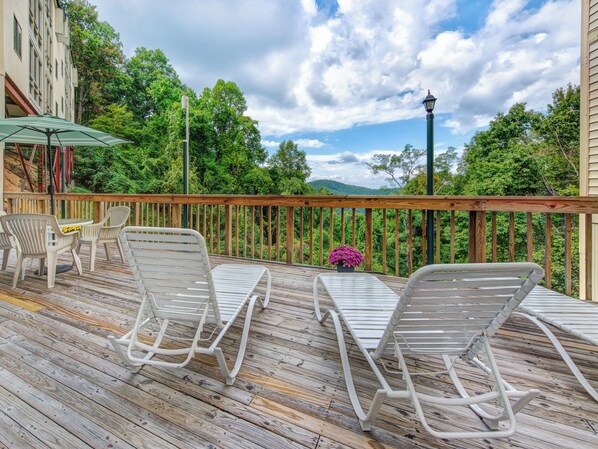 A wooden deck with outdoor furniture, a table, and chairs. - Bear Cub Retreat by Jackson Mountain Rentals (Gatlinburg)