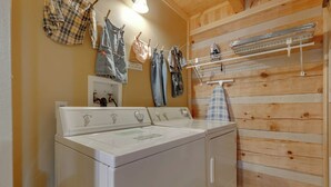 Un espace buanderie équipé d’un lave-linge et d’un sèche-linge à chargement frontal, avec des murs en bois et un étendoir à linge.