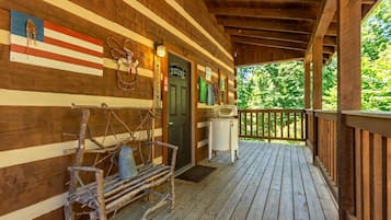 A wooden cabin with a porch, a welcome sign, and a flag.