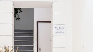 A hotel lobby with a staircase leading to the first floor, a sign indicating 'Nue Rooms', and potted plants. - Nùe Rooms (Cagliari)