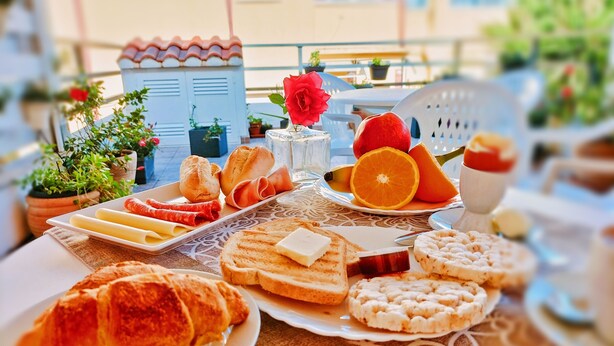 A table with various breakfast items including bread, pastries, fruits, and cheese. - Nùe Rooms (Cagliari)