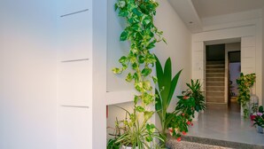 A modern indoor space with a staircase, potted plants, and a white wall with horizontal lines. - Nùe Rooms (Cagliari)