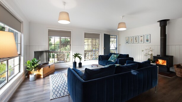A modern living room with a large blue sofa, a fireplace, and large windows.