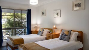 A double room with two beds, a window with curtains, and two bedside lamps.