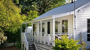 A white house with a covered porch and a staircase leading to the entrance.