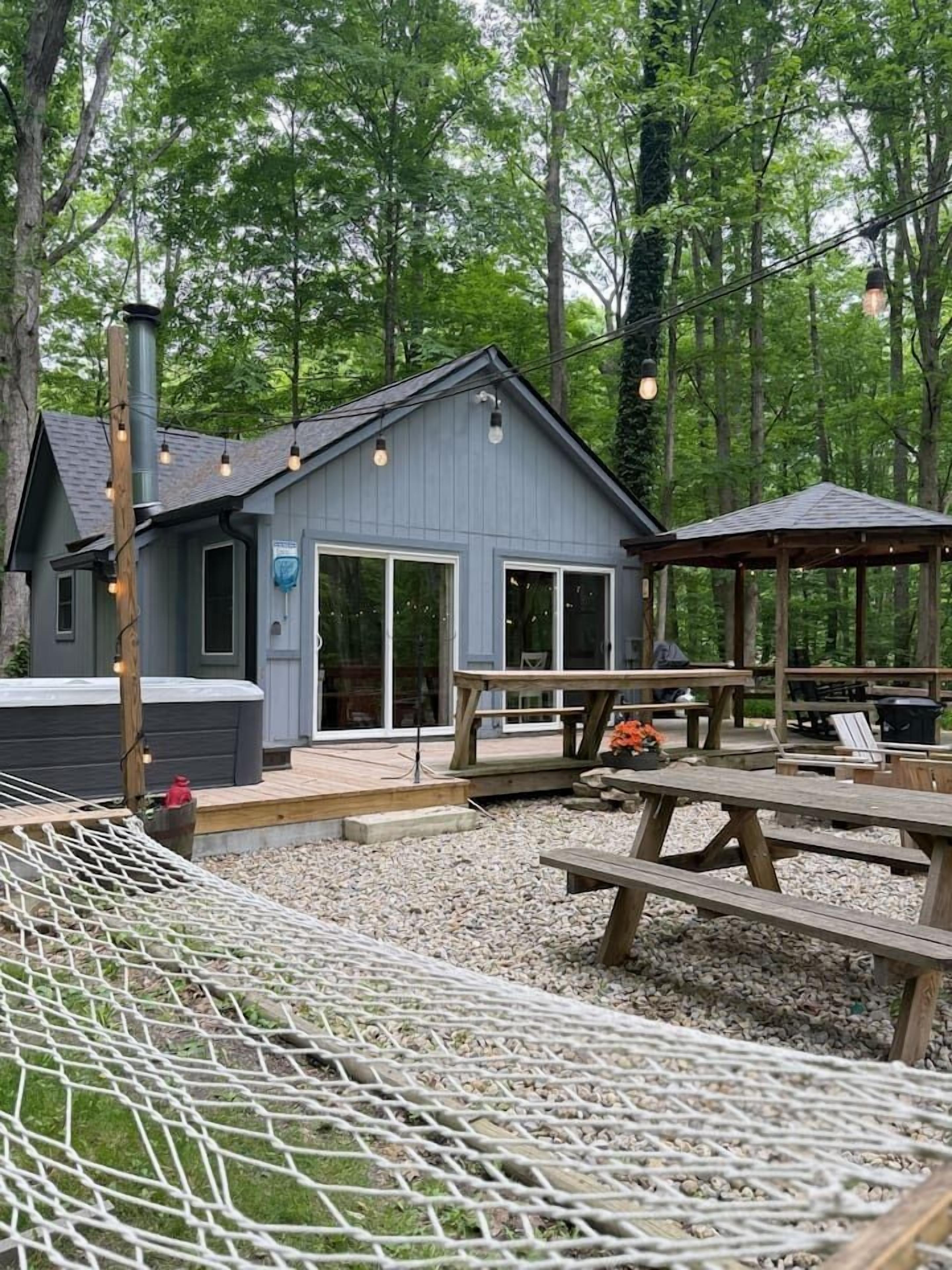 A cabin with a deck, outdoor seating, and a hammock.