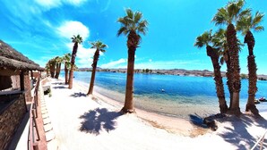Een strand met palmbomen en een helderblauwe lucht.