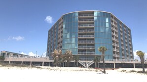 A modern, multi-story hotel with a curved facade, balconies, and a staircase leading to the entrance.