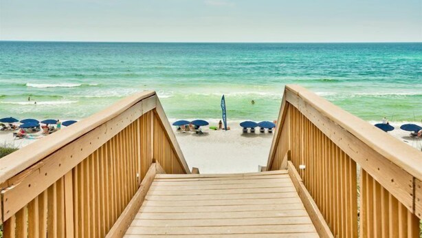 A wooden boardwalk leading to a beach with umbrellas and people. - High Pointe Overlooking Lagoon Pool, Gulf Views! (Rosemary Beach)