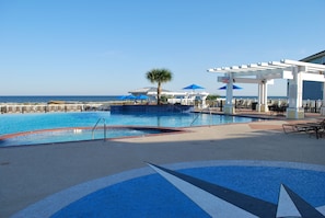 Relax by the pool with ocean views, surrounded by a pergola and lounge chairs.