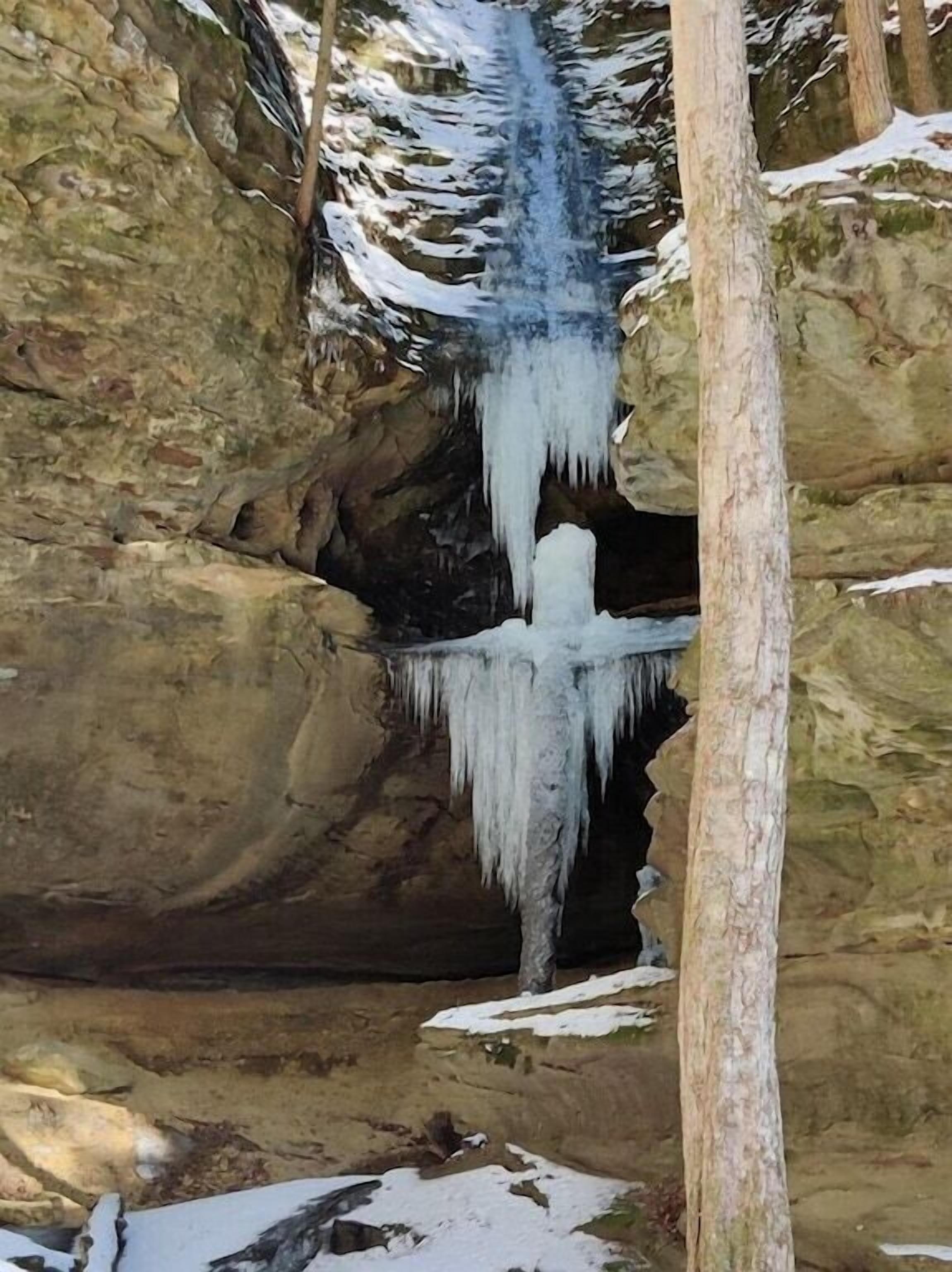 A natural rock formation with a waterfall and icicles.