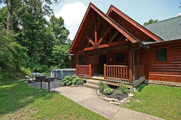 Eine Blockhütte mit Veranda, Picknicktisch und Grillplatz.