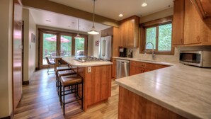 A modern kitchen with wooden cabinets, stainless steel appliances, and a central island with stools. - The Breckenridge Bicycle House - One Mile to Main St and the gondola (Breckenridge)