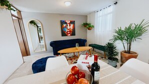 A modern living room with a dining area, featuring a sofa, a coffee table, and a dining table with a bowl of apples and a bottle of wine. - 2 Bed in the heart of Cholula with views to the Pyramid and the (San Andrés Cholula)