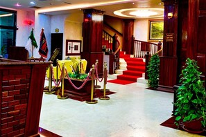 A lobby with a red carpet, a staircase, and a reception desk.