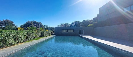 A clear swimming pool with a modern building in the background.