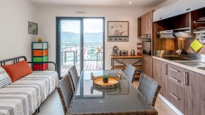 Una cucina moderna con zona pranzo, un balcone con vista e un piccolo tavolo con sedie.