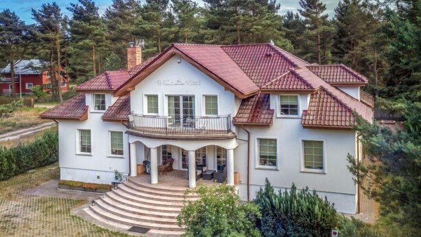 A two-story house with a balcony, a covered porch, and a well-maintained garden.